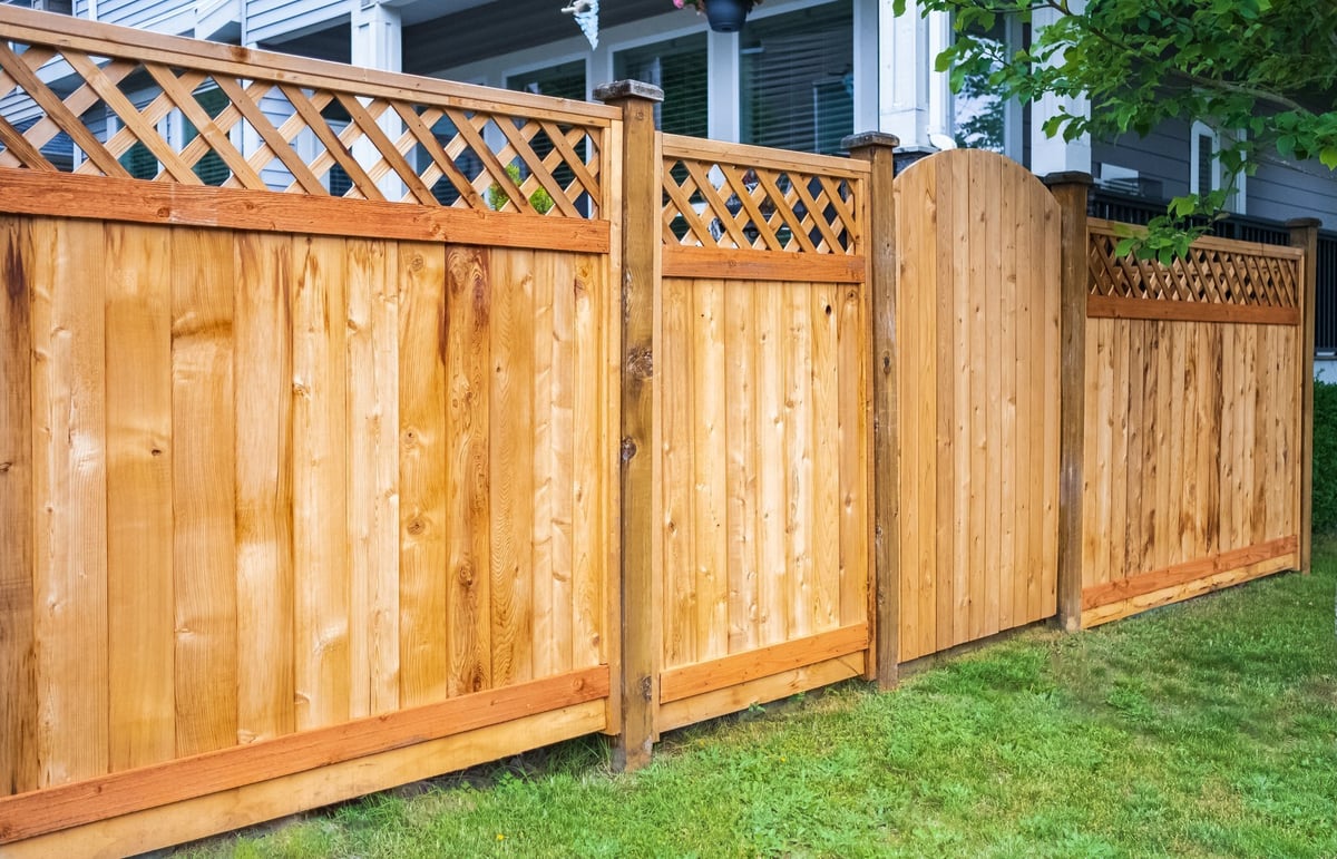 Nice wooden fence around house. Wooden fence with green lawn. Street photo, nobody, selective focus