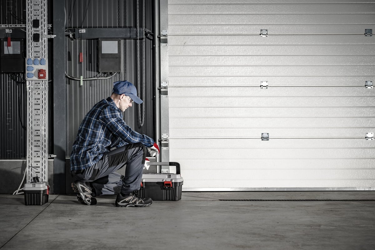 Caucasian Technician in His 40s Servicing Commercial Dock Garage Gate. Industrial Theme.