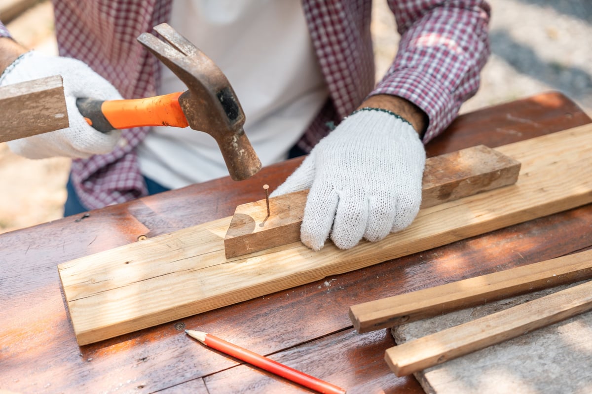 Portrait carpenter man working on DIY woodworking project at home workshop. Skilled craftsman using tools for handmade furniture, home improvement and sustainable lifestyle concept.